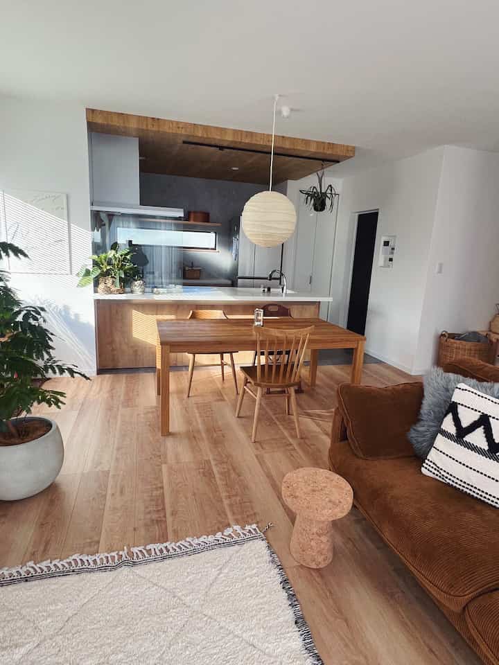 ナチュラルウッドトーンと白い壁のリビングとキッチン、木製のダイニングテーブルとソファが調和した温かみのある雰囲気のあるインテリア