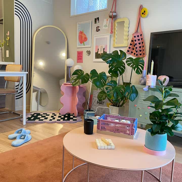 ピンクとホワイトの色調のリビングとダイニング、グリーンプラントと個性的な家具が調和した温かみのある空間