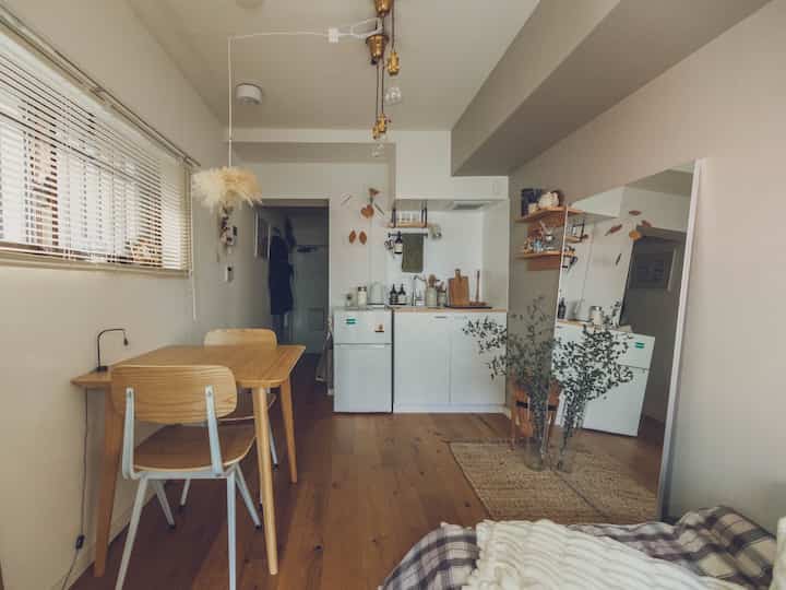 Natural-colored and wood-toned 8-tatami studio apartment featuring wall-mounted shelves, large full-length mirror, creating a cozy home cafe style with spacious feel