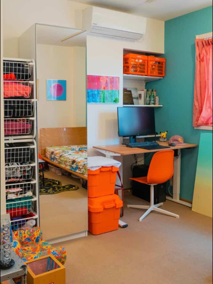 A single household home office space with white and blue accent walls, featuring an orange chair and storage boxes in a cozy workspace