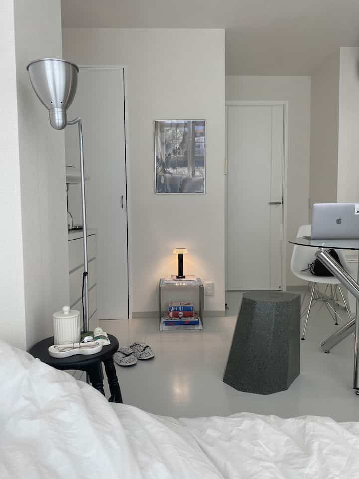 White-toned compact living room featuring a modern stool, floor lamp, and neat interior design
