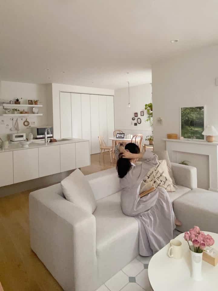 白を基調としたナチュラルな木目調のリビング、ソファとローテーブルが配置された雰囲気のある空間