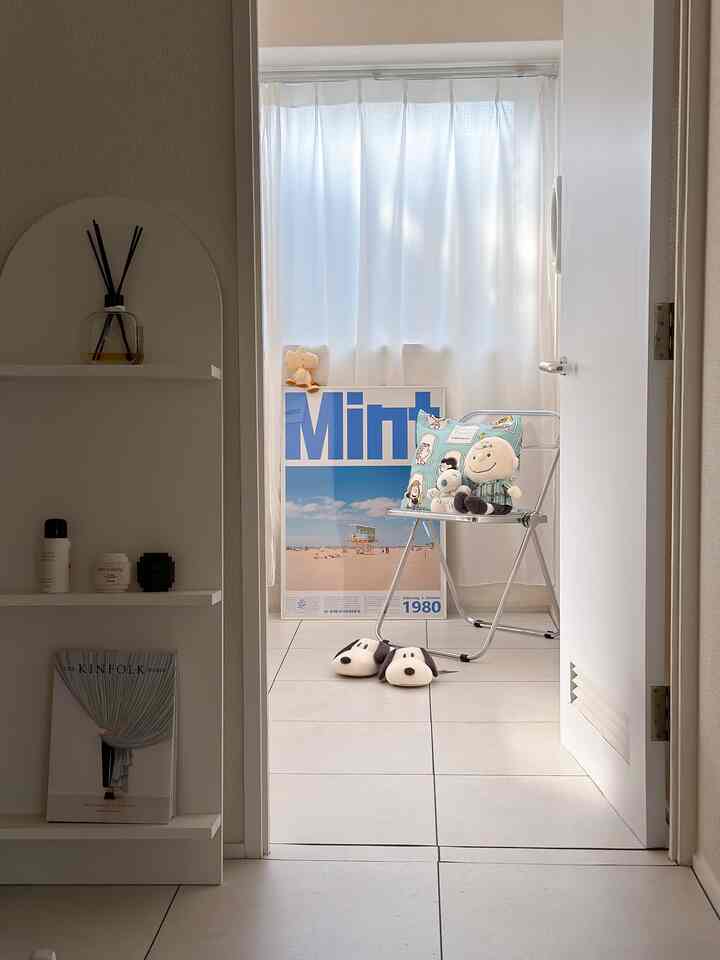 明るい白色調の小さな部屋、透明な折りたたみ椅子にスヌーピーのぬいぐるみとスリッパが置かれた、清潔感のあるインテリア