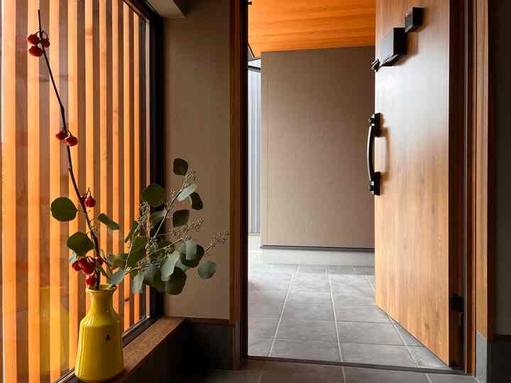 Wood tone and beige entrance featuring a yellow vase with greenery and natural light, creating a warm atmosphere