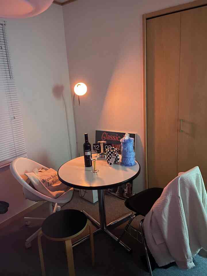 Warm small single household home bar illuminated by orange floor lamp, featuring round table and chairs in a cozy room