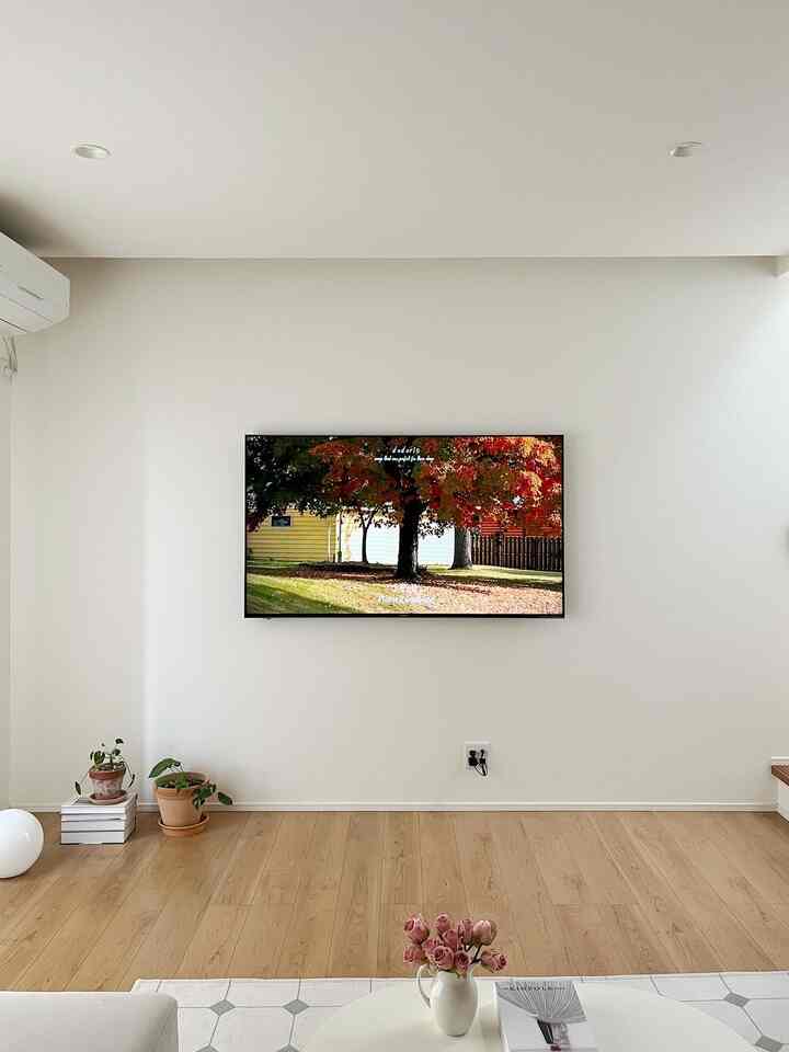 白い壁と木目調の床のミニマルなリビング、ソファとローテーブルに観葉植物が調和する雰囲気のあるインテリア