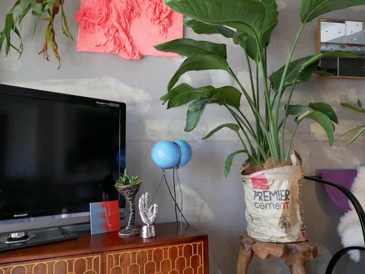 ナチュラルな色調のリビング、中央にブルーのバブルランプと大きな観葉植物が配置された雰囲気のある空間