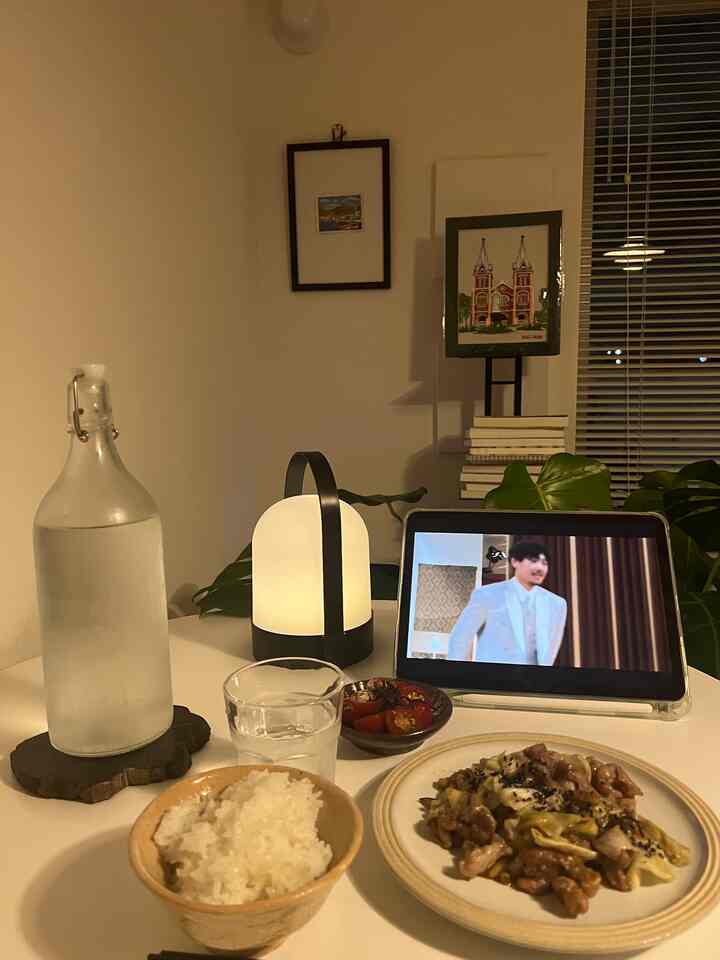 暖かな照明と白いテーブルがある一人暮らし向けのおうちカフェ空間、健康的な食事とデジタル機器が配置されている