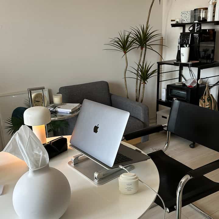 Modern dining room in white and gray tones featuring sofa and coffee machines with a clean atmosphere