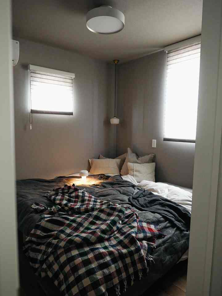 Gray toned bedroom featuring a bed with pillows and a table lamp at center, creating a cozy atmosphere