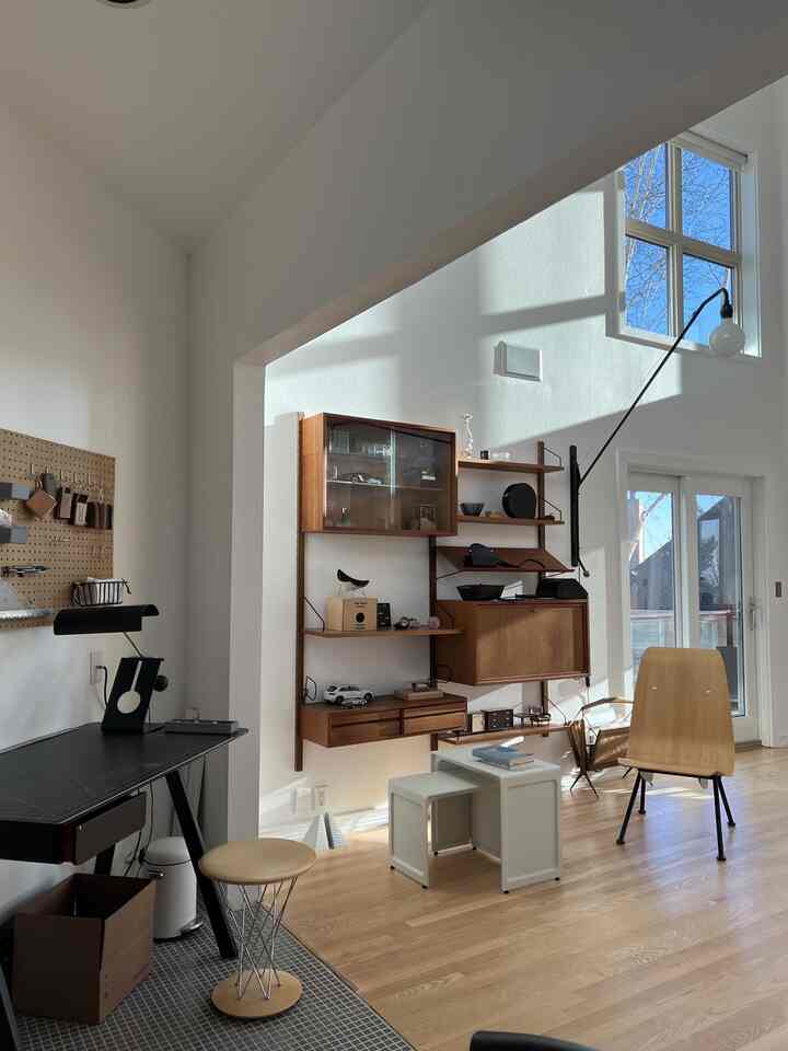 Bright white and wood tone home office featuring wall shelves, desk, and chairs in a natural atmosphere