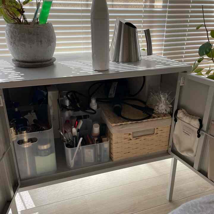 White-toned vanity cabinet organized with transparent containers and a wicker basket in a tidy interior space