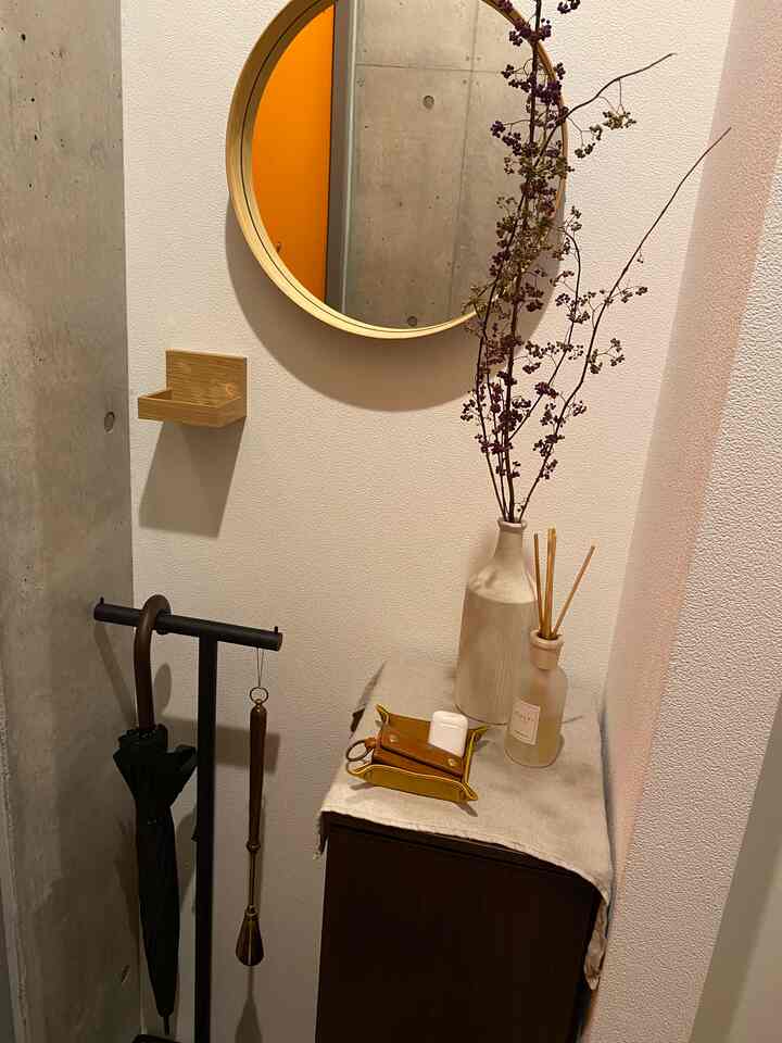 ベージュと木目調の玄関、丸い鏡とドライフラワー、ディフューザーが調和した自然な雰囲気のあるインテリア