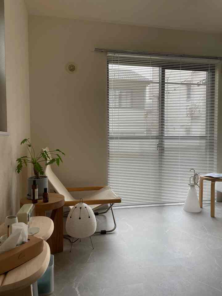 Natural tones and white small room featuring lightweight wooden armchair and blinds, creating a clean and cozy atmosphere