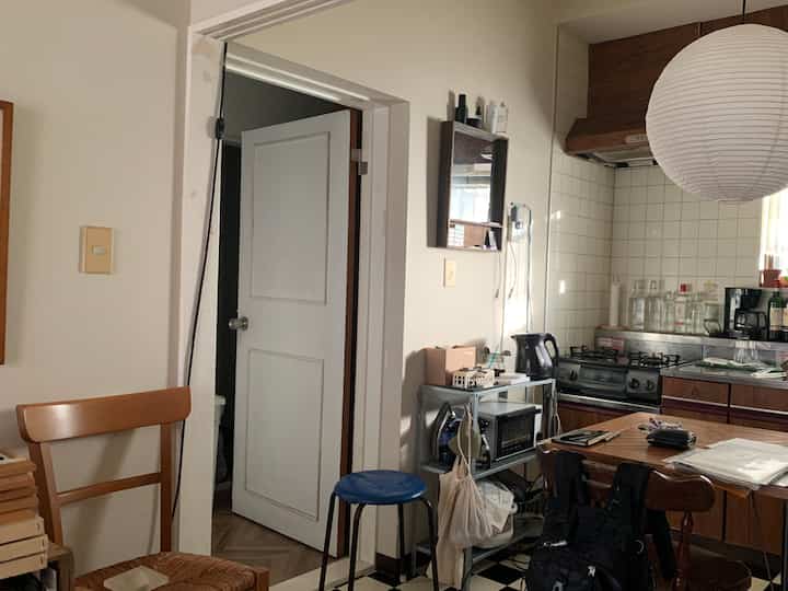 白い壁と木製のダイニングテーブルが配された、やや散らかった雰囲気のある居心地の良いキッチン空間