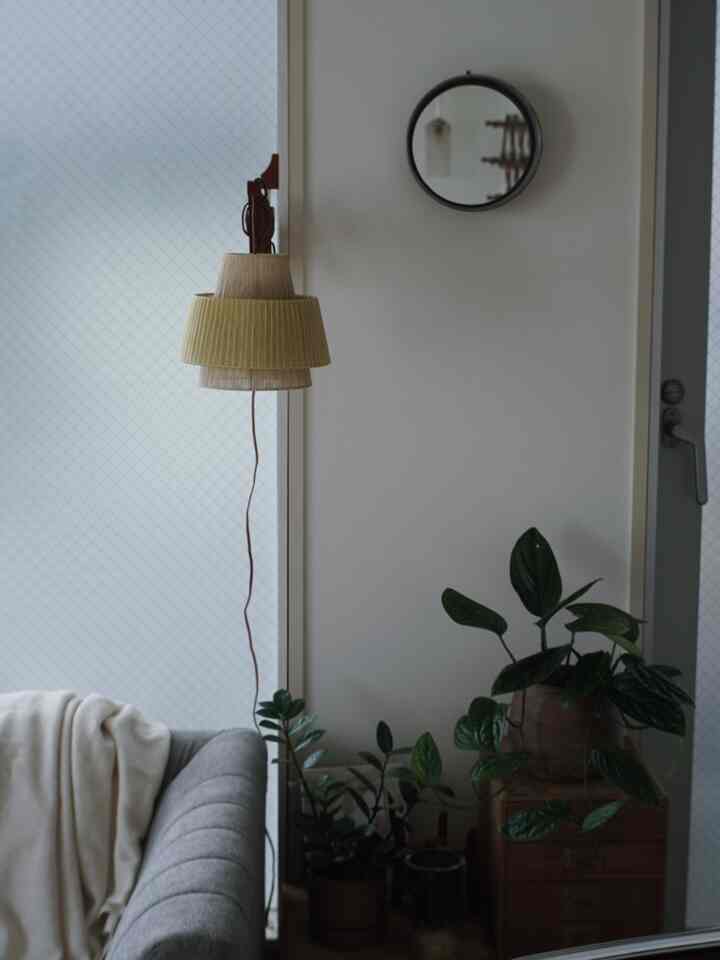 Soft beige and grey toned living room balcony featuring an antique scissor lamp and lush indoor plants for a natural atmosphere