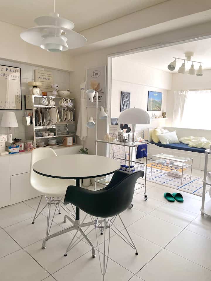 白を基調としたダイニングとリビングが繋がる、モダンな家具と寝具が配置された明るく居心地の良い空間