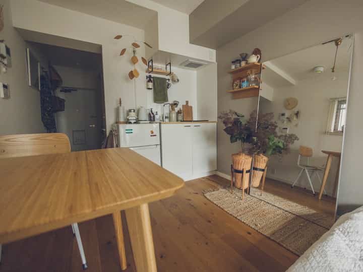 Natural wood tone dining room and kitchen space featuring a large mirror and tidy storage ideas with simple interior design