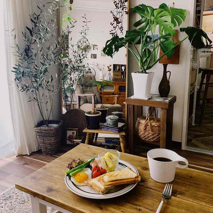 Natural wood tone and white walled home cafe space featuring a dining table with breakfast and coffee, creating a cozy atmosphere