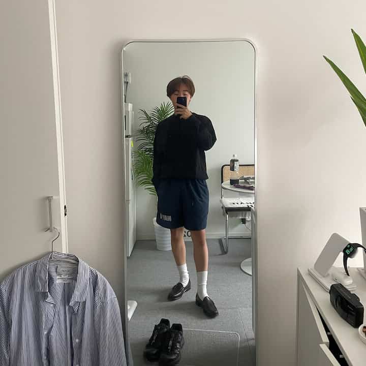 白とグレーの色調のワンルーム、特徴的な大きな鏡とダイニングテーブルが配されたシンプルで自然な雰囲気のあるインテリア