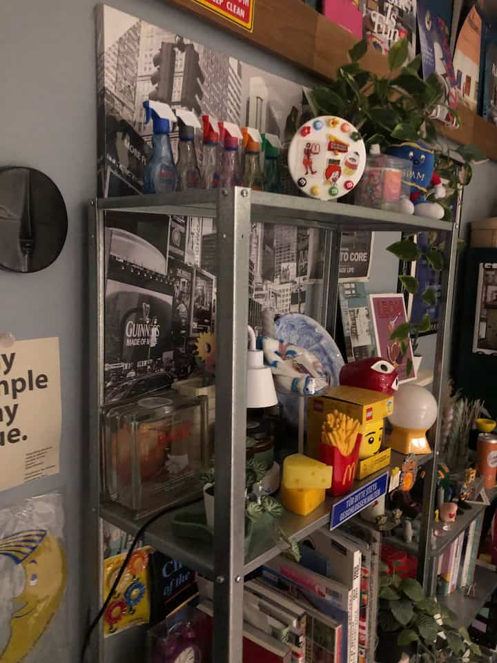 Natural-tone small room interior featuring metal shelf with transparent glass decorations and various objets