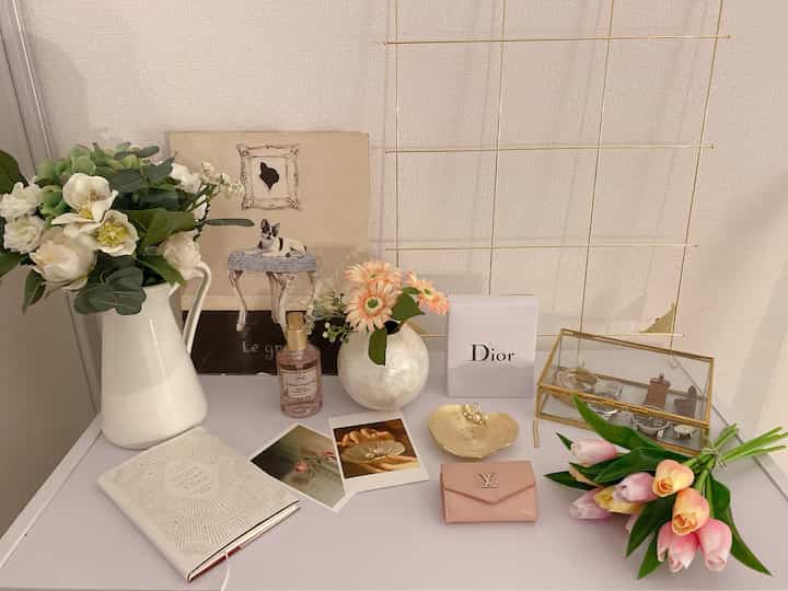 白とピンクのトーンで飾られたトイレ上のアクセサリーと花瓶が配置された雰囲気のある空間