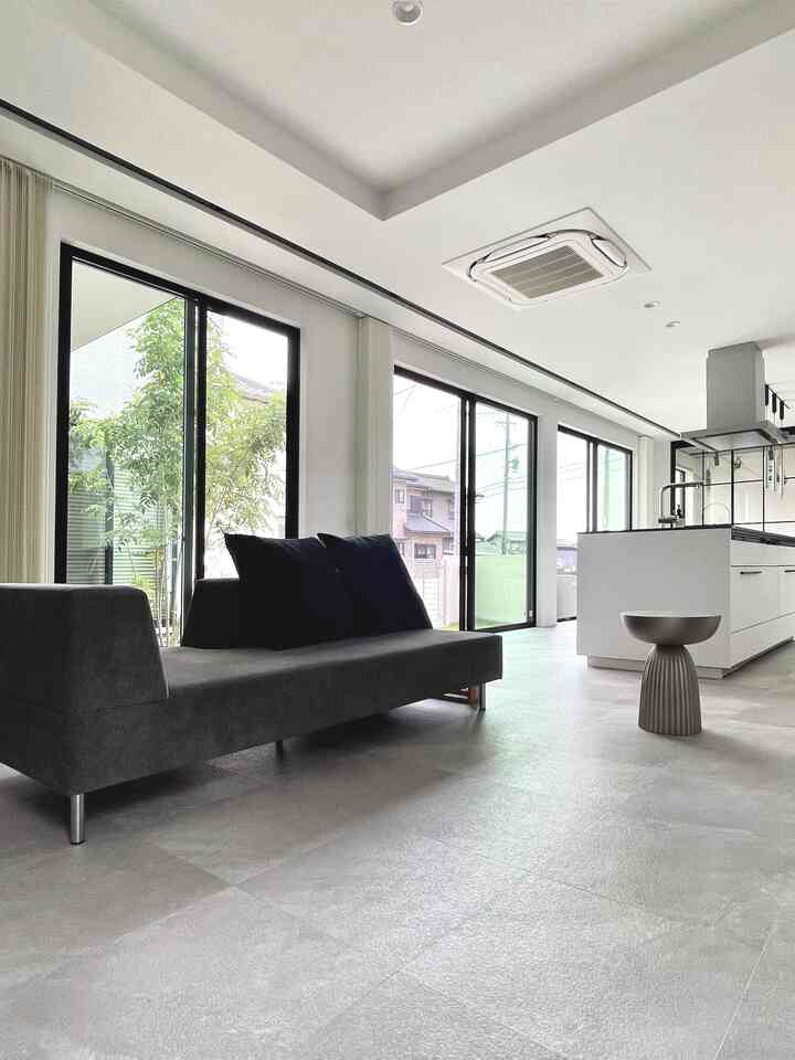 白と黒のトーンで統一されたモダンなオープンプランのリビングとキッチン、大きな窓から自然光が差し込む雰囲気のあるインテリア