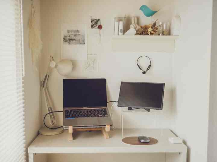 White-toned compact workspace featuring a simple desk, wall shelf with stationery, and modern interior design