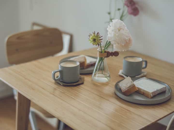 ナチュラルな木目調のダイニングルーム、シンプルな木製テーブルにグレーのマグカップが置かれている印象的な空間