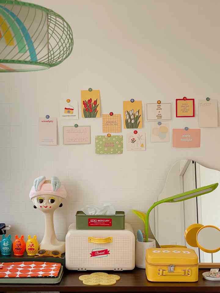 白い壁と黄色の小物があるシンプルな化粧台スペース、壁にはかわいいポスターが貼られ、雰囲気のあるインテリア