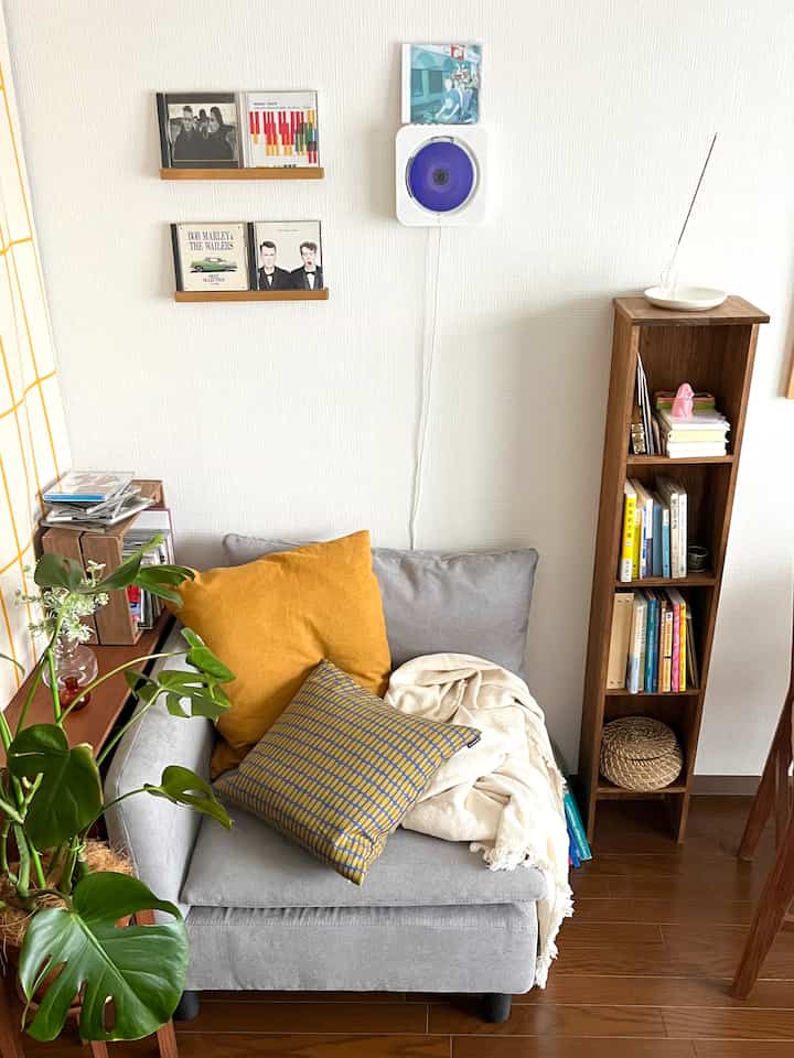 ブラウンの木製フロアとグレーのソファが配置されたナチュラルなリビング、クッションと植物が温かみのある雰囲気を作るインテリア