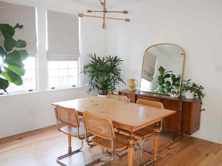 Bright white background dining room featuring brown wooden furniture, large mirror, and plants with natural modern atmosphere