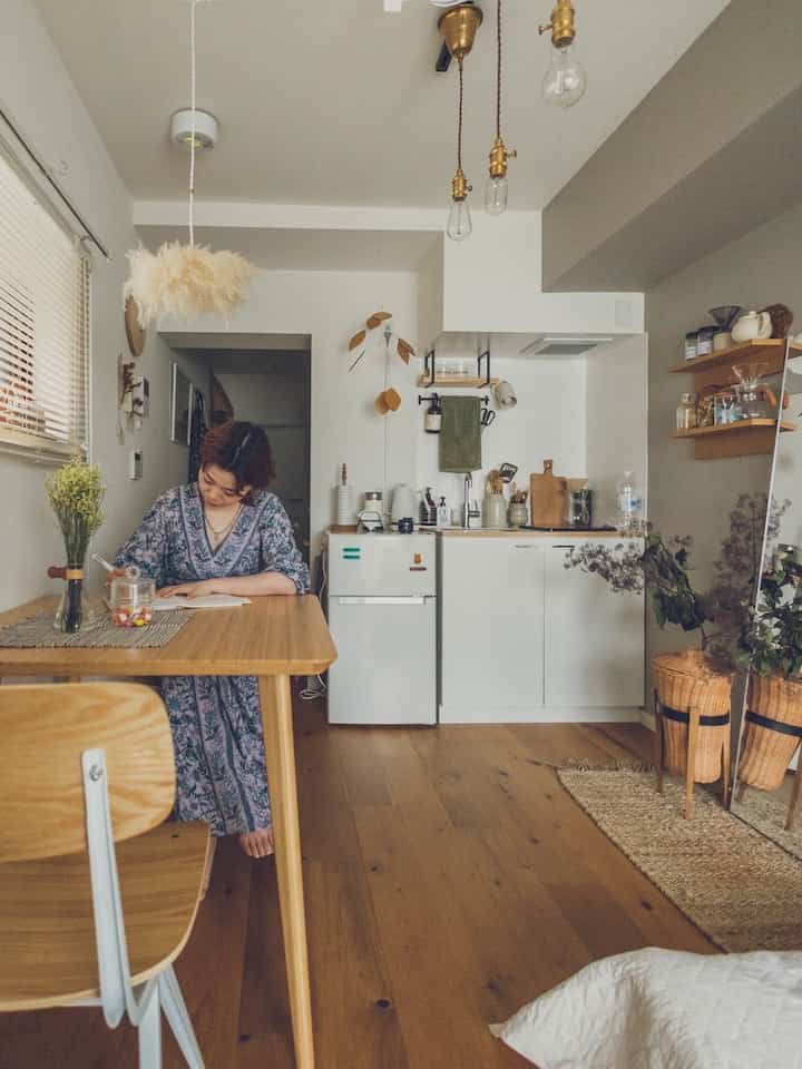 ナチュラルな色調の6畳のダイニングとキッチン、木製のテーブルと植物が配置された落ち着いた空間