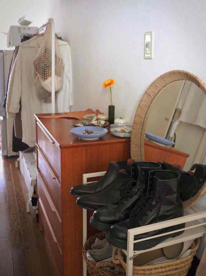 ブラウンの木目調と黒い靴が並ぶ狭い玄関の収納スペース、クローゼットとチェストが配置されたナチュラルな雰囲気のインテリア