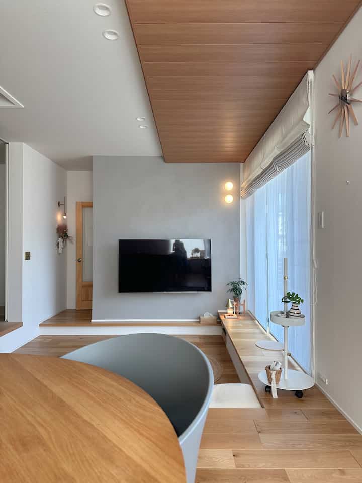 ナチュラルな木目調とホワイトのリビング、窓際のベンチとアームチェアが配置されたモダンで明るいインテリア