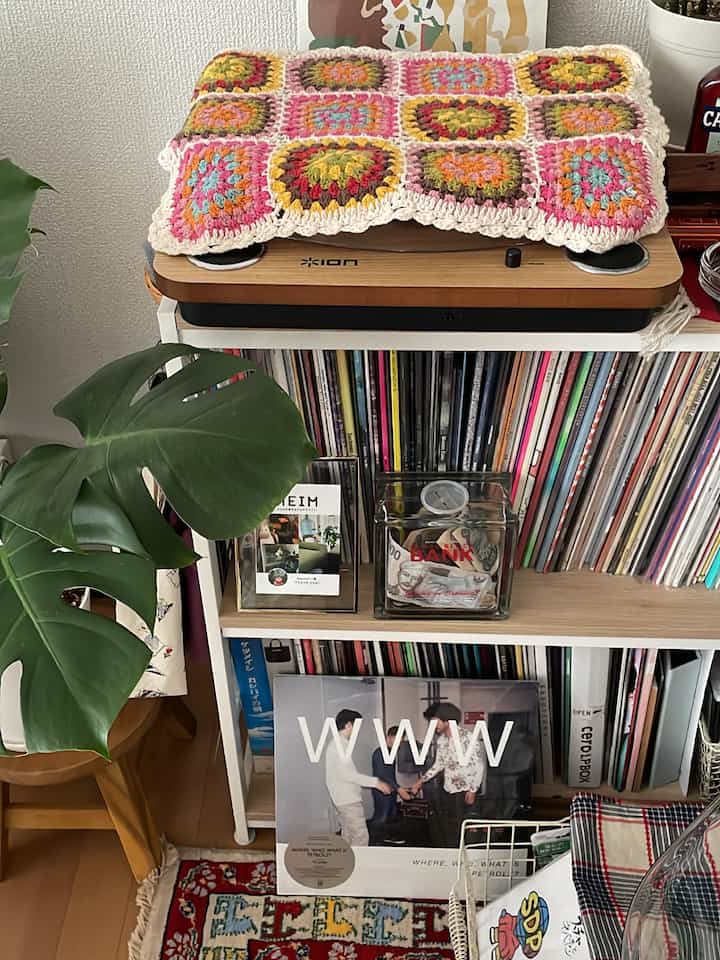 Colorful retro-style music space featuring a bookshelf filled with vinyl records, a wood tone stool, and a record player creating a cozy atmosphere