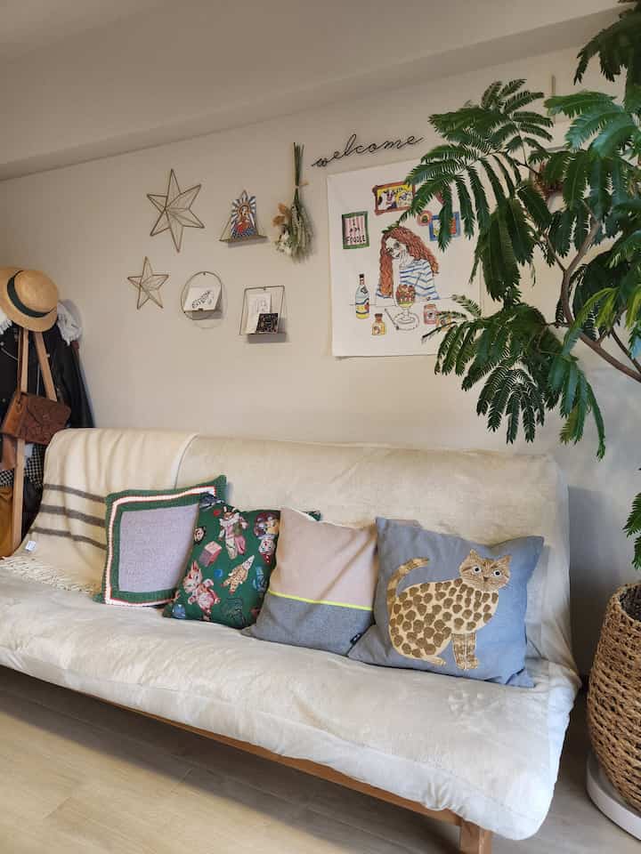 Beige-toned sofa bed with cushions in an 8-tatami living room, natural plants and wall decor create a cozy natural space