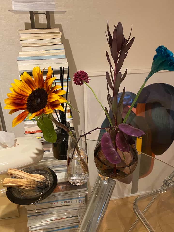 ブラウンとナチュラルカラーのダイニング、花瓶に飾られたヒマワリなどの植物が配置された雰囲気のあるインテリア