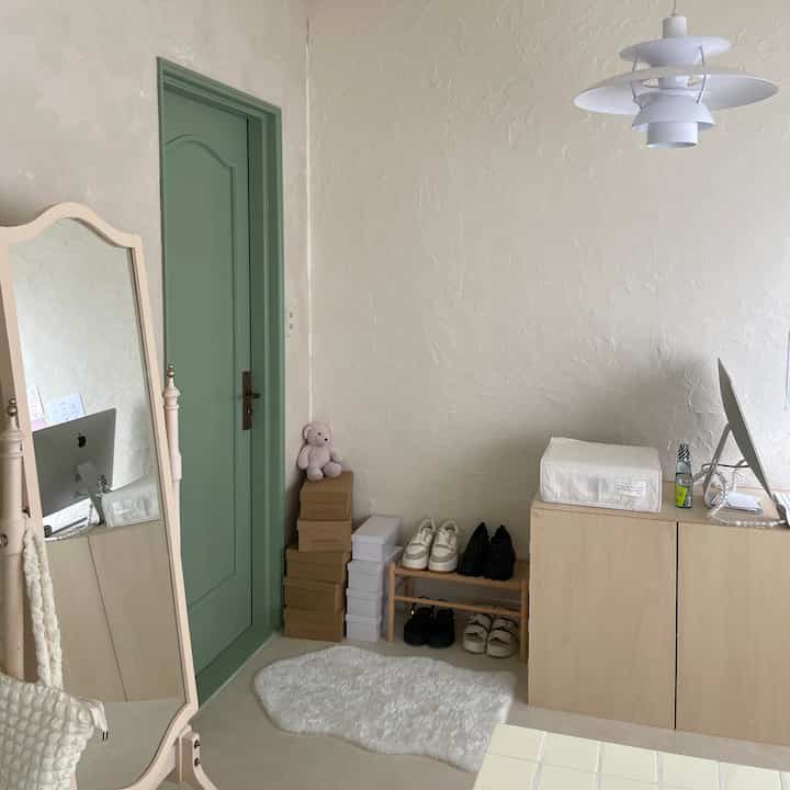 白とミント色調の玄関、シンプルな鏡とラグ、収納キャビネットと靴棚が配置された落ち着いた雰囲気のインテリア