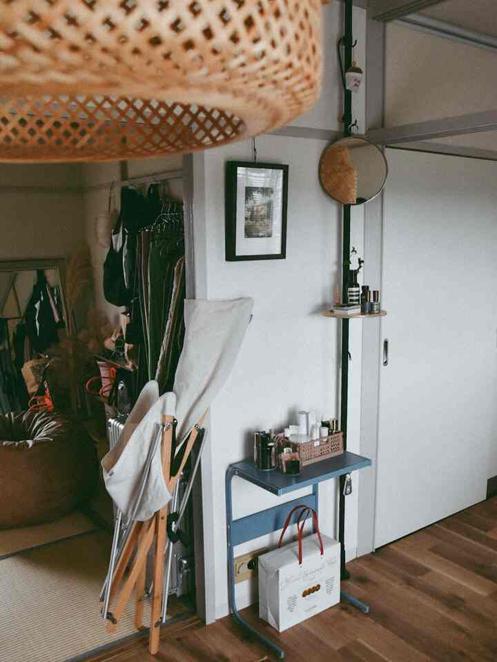 Natural wood tones and white walls define a compact studio apartment space featuring a folded Take! Chair and picture frame with cozy ambiance