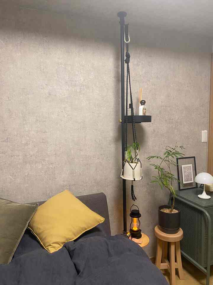 ナチュラルカラーの一人暮らしの狭い部屋、黄色いクッションとスツール、植物が配置された落ち着いた空間
