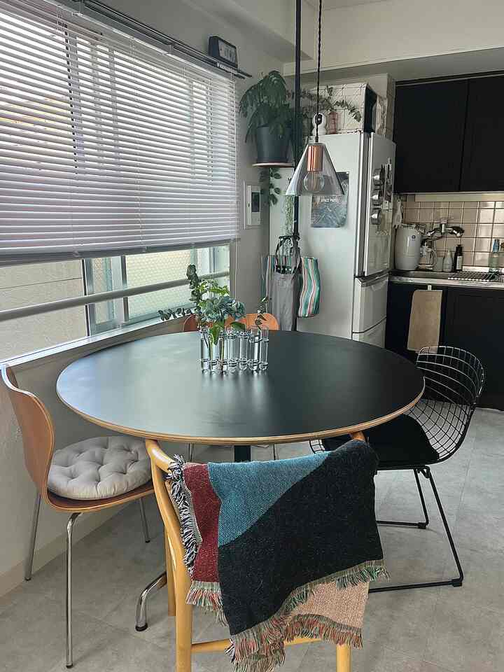 A natural modern dining room with black and wood tones featuring a round dining table and various chairs creating a stylish space