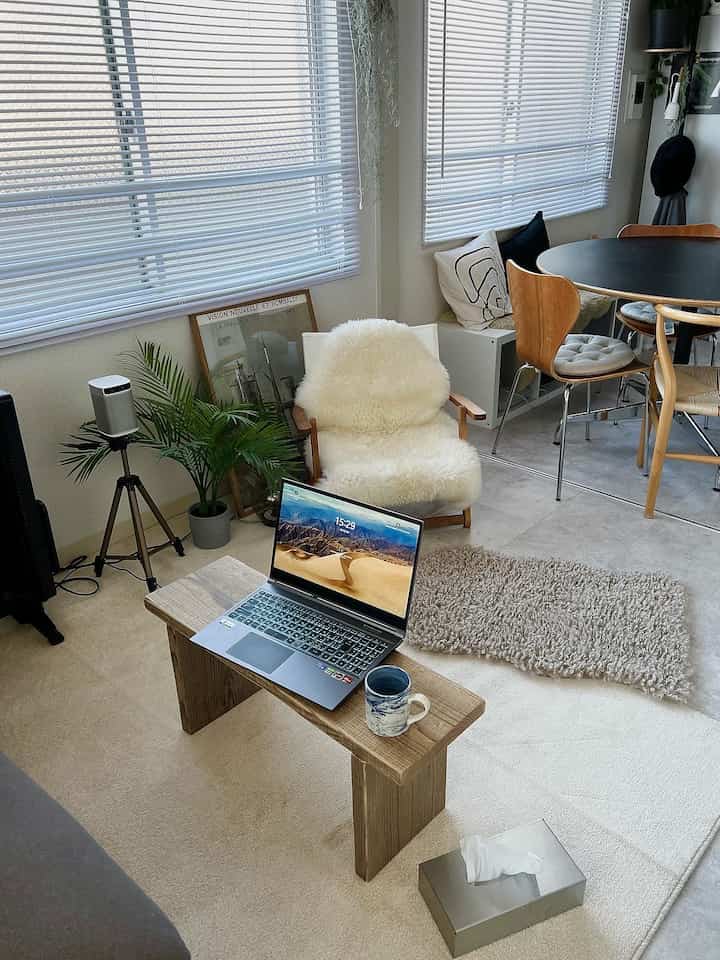 ベージュと白を基調としたリビング、木目調のコーヒーテーブルとアームチェア、フェイクグリーンが配置されたナチュラルな雰囲気のインテリア