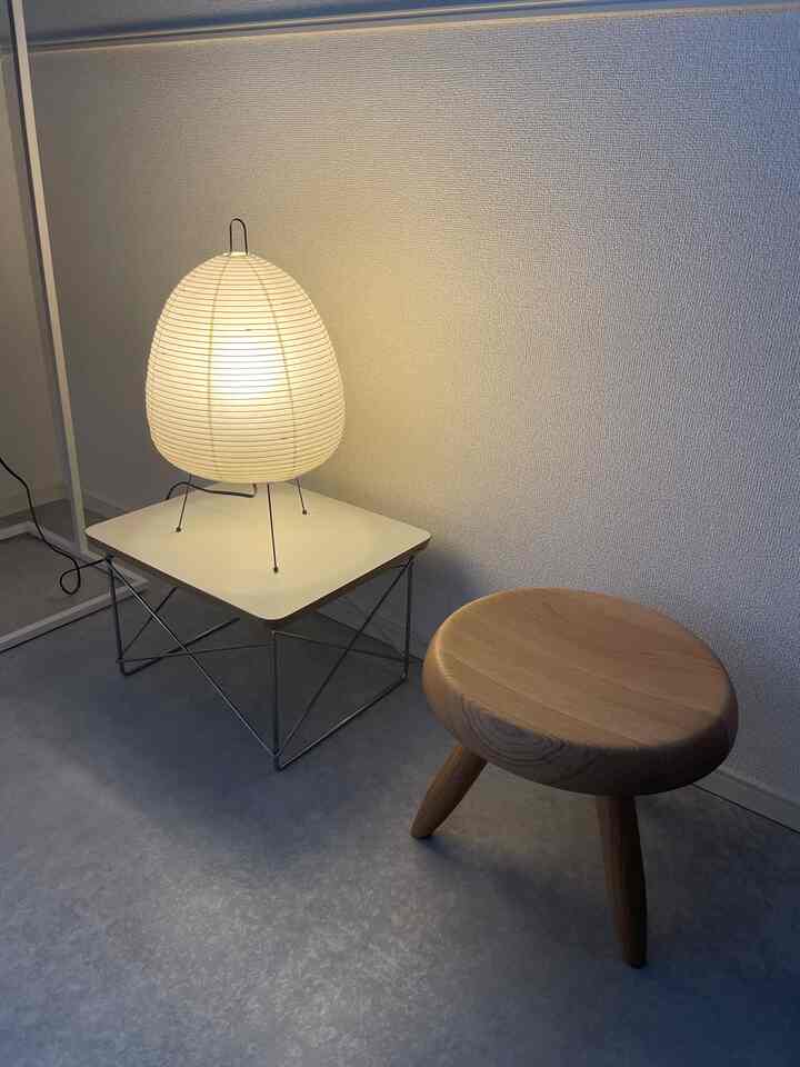 Minimal space with natural wood stool, white side table, and soft warm lighting