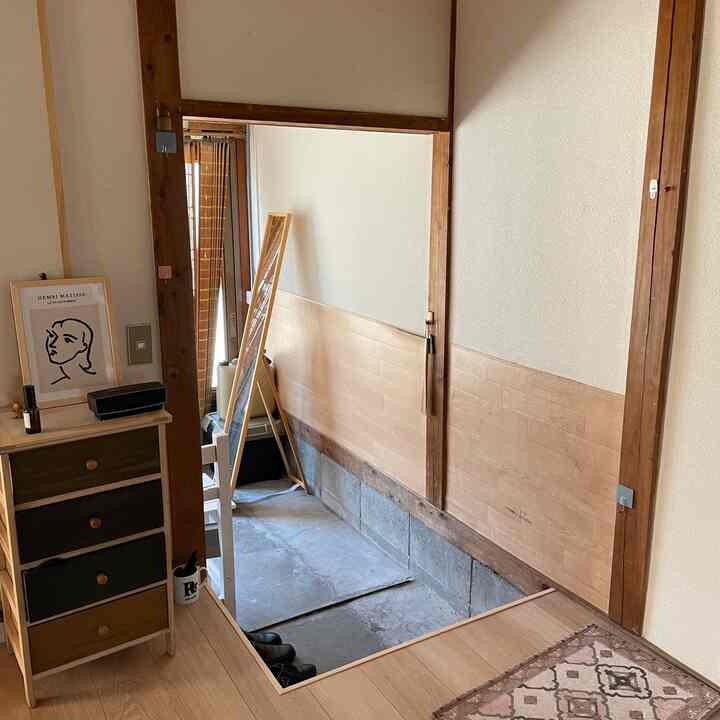 ナチュラルな木目調と白が調和する小さな玄関、全身鏡とポスターが配置された雰囲気のある空間