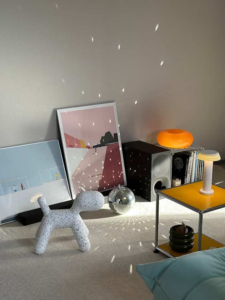 ベージュとイエローの色調のリビング、白い犬の形のオブジェとポスター、サイドテーブルが配置された雰囲気のある空間