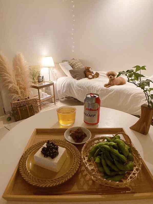 白とベージュのトーンが調和した小さな寝室、ベッドとテーブルにビールと軽食が配置された雰囲気のあるインテリア