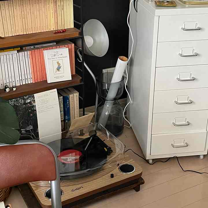 ナチュラルな色調のリビング、レコードプレーヤーと本棚、白いチェストが配置されたモダンで落ち着いたインテリア