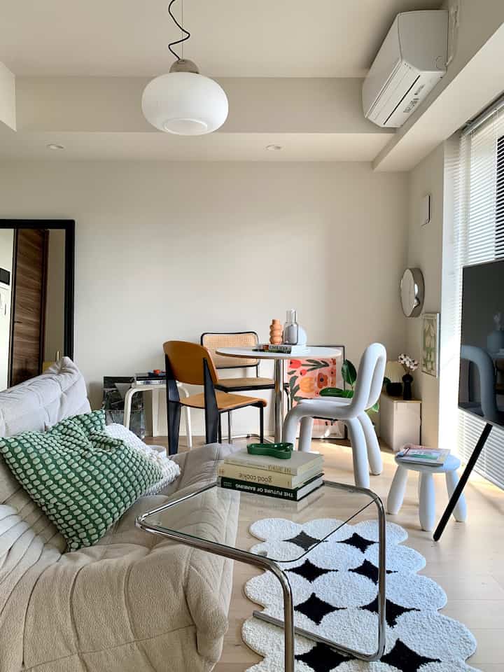 ナチュラルな色調のリビング・ダイニング空間、さまざまな椅子とベージュのソファが配置された落ち着いた雰囲気のインテリア