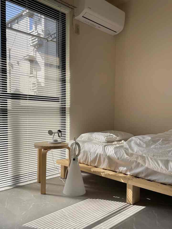 Minimal bedroom with white and wood tones, featuring blinds softly filtering natural light